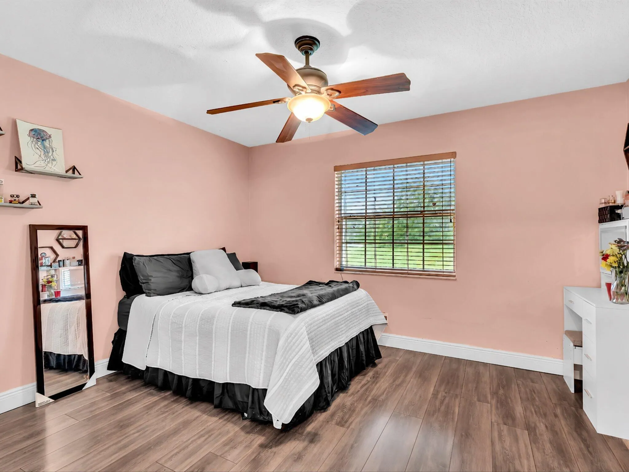 Wood-finish flooring, ceiling fan with integrated lighting, single window with blinds, and built-in shelving