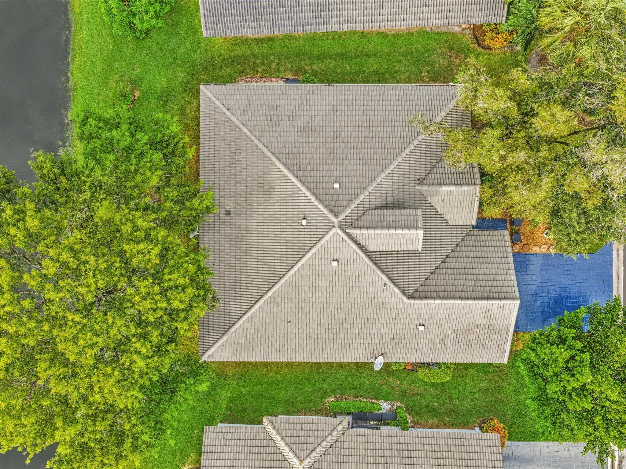 Terracotta tile roofing, expansive green lawn, mature trees, and a private swimming pool