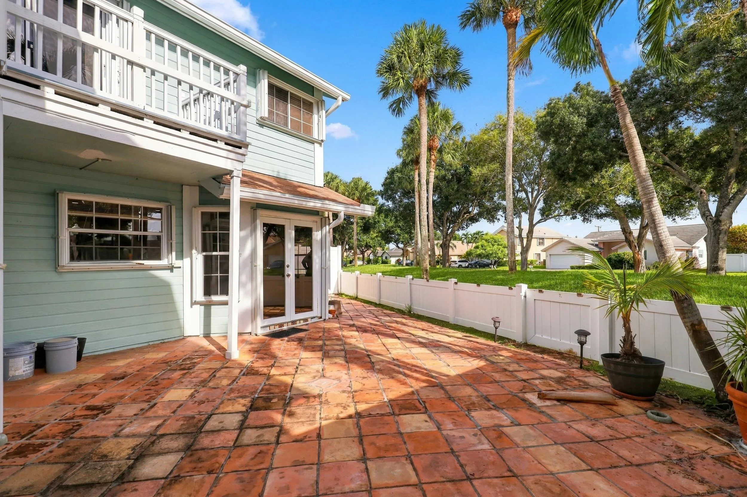 The private backyard is designed for effortless Florida living, featuring an expansive Spanish tile patio with a covered area for year-round enjoyment. A brand-new white PVC fence provides a secure space for pets while preserving views of the surrounding green spaces and mature trees. Perfect for barbecues, entertaining, and relaxed indoor-outdoor living.