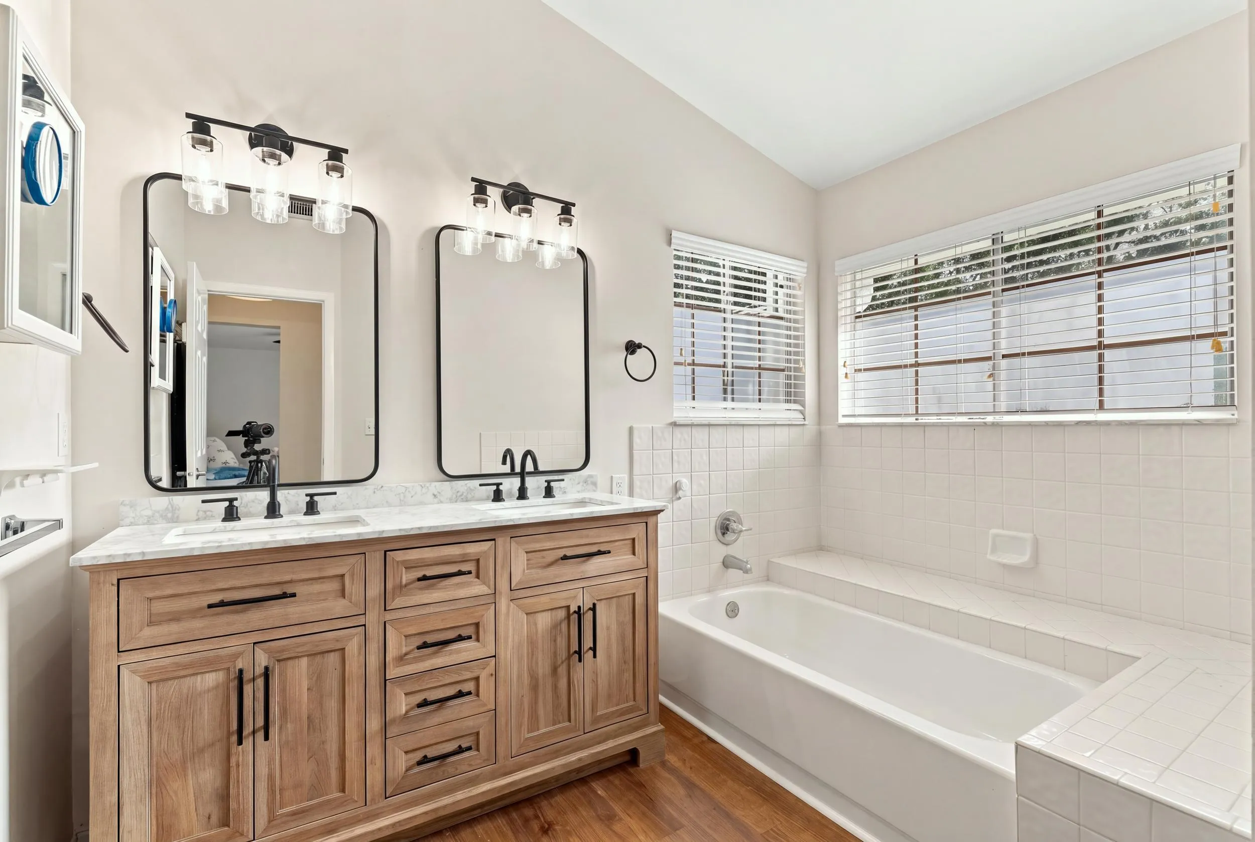 The fully updated primary ensuite exudes refined elegance with a natural oak vanity, quartz countertops, new fixtures, a relaxing bathtub, and a beautifully finished shower with a frameless glass enclosure.