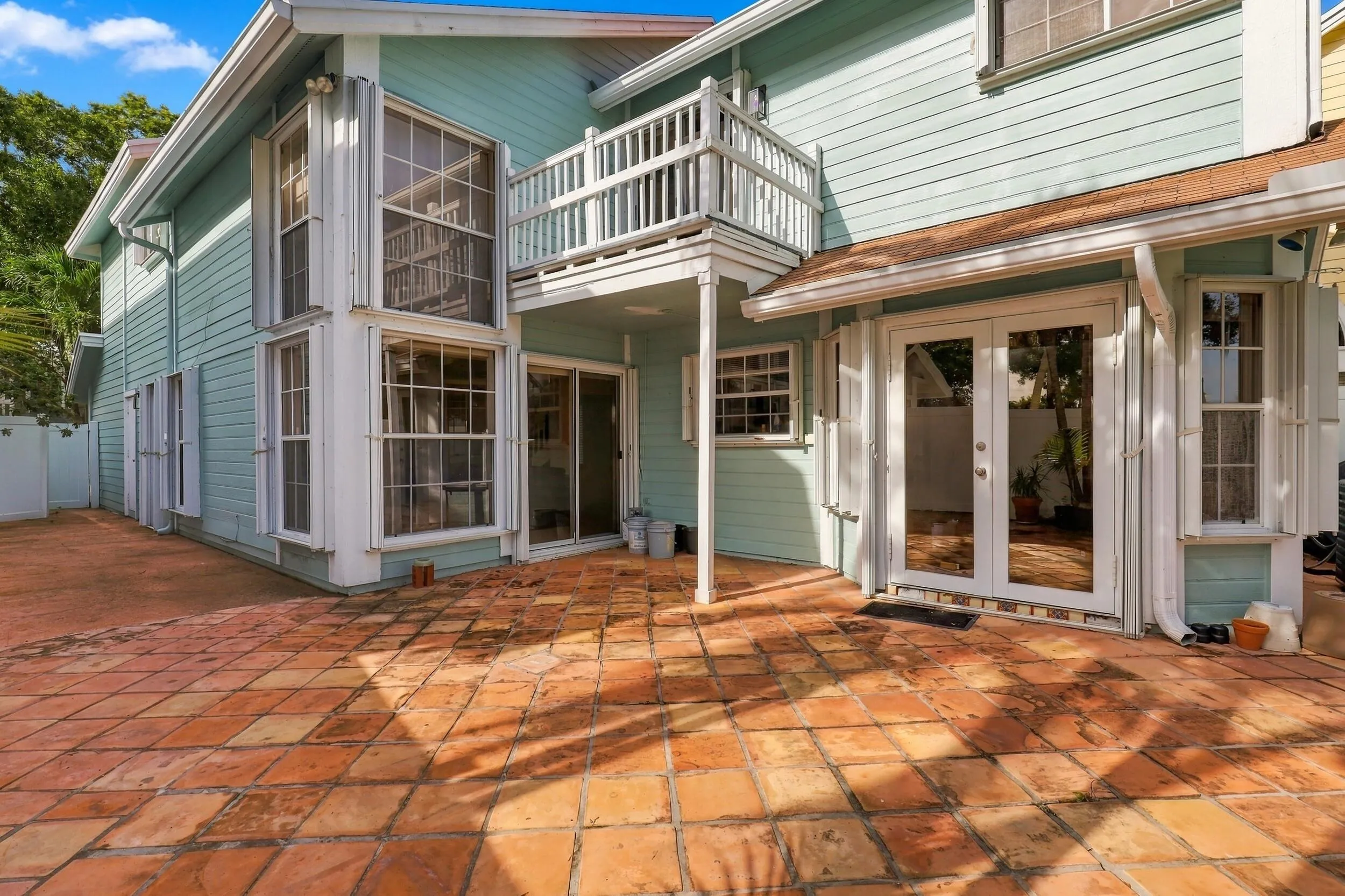 The private backyard is designed for effortless Florida living, featuring an expansive Spanish tile patio with a covered area for year-round enjoyment. A brand-new white PVC fence provides a secure space for pets while preserving views of the surrounding green spaces and mature trees. Perfect for barbecues, entertaining, and relaxed indoor-outdoor living.