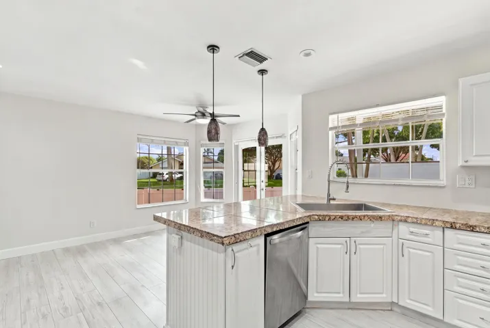 The bright eat-in kitchen features contemporary white cabinetry, granite countertops, new stainless steel appliances, and a convenient breakfast bar. Abundant natural light, space for casual dining, and sliding glass doors create a seamless connection to the private backyard.