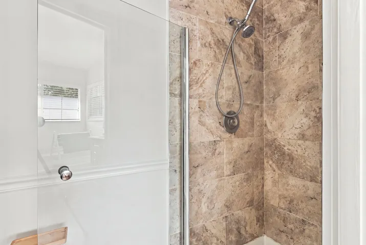 The fully updated primary ensuite exudes refined elegance with a natural oak vanity, quartz countertops, new fixtures, a relaxing bathtub, and a beautifully finished shower with a frameless glass enclosure.