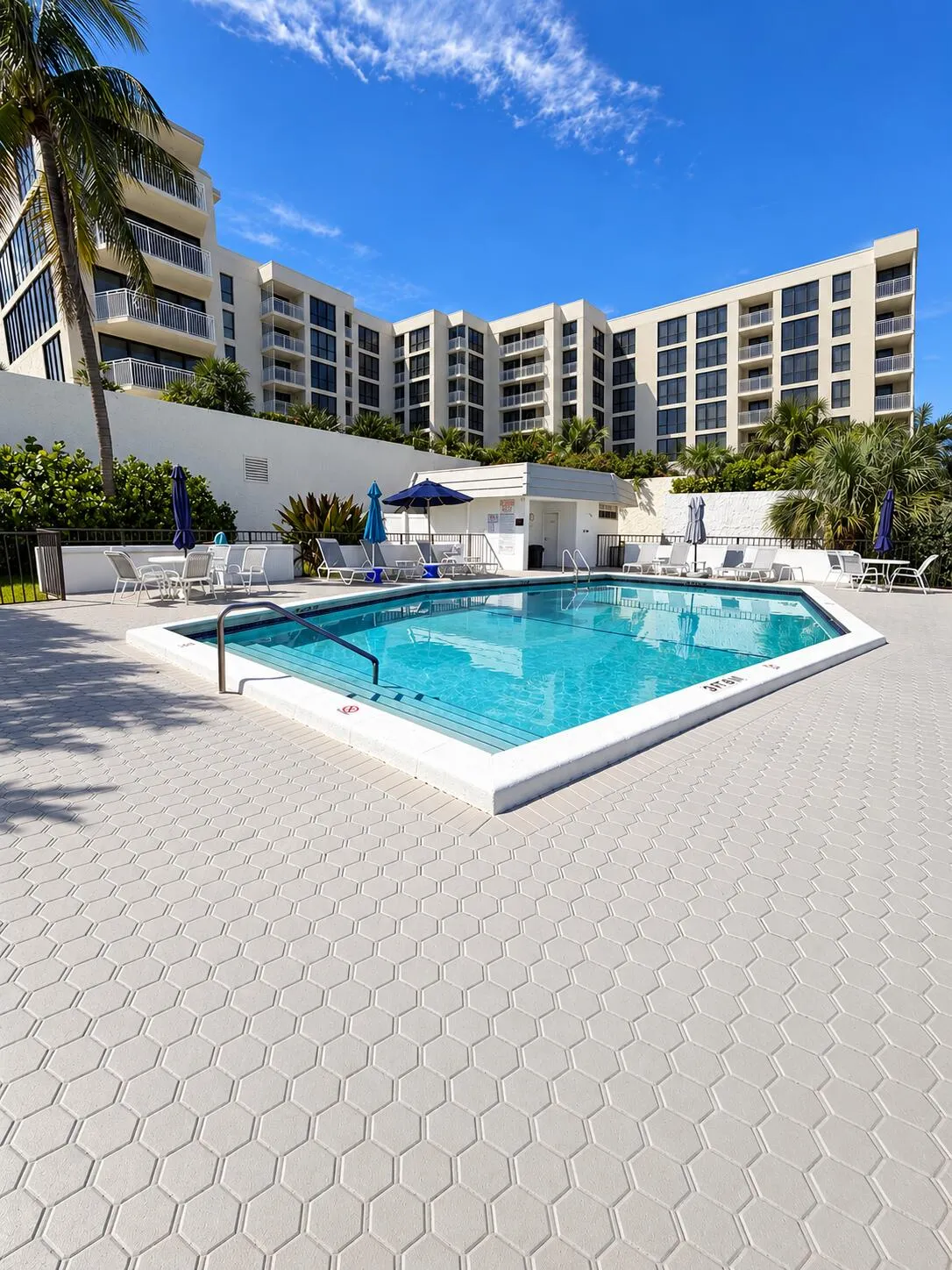 Heated pool with lounge chairs, umbrellas and tables. There are bathrooms and a sauna.