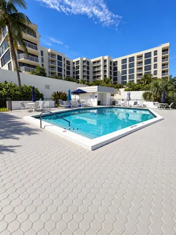 Heated pool with lounge chairs, umbrellas and tables. There are bathrooms and a sauna.