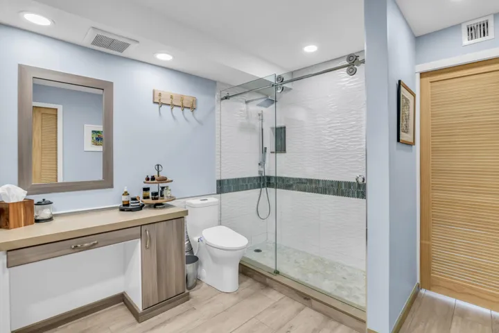 The toilet has an electric bidet with water temperature settings. Beautiful tile work in the shower, niche and rolling frameless glass doors.