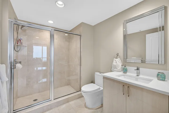 En-suite bathroom features a sleek glass-enclosed shower,offering a clean, contemporary aesthetic that blends functionality with understated elegance.