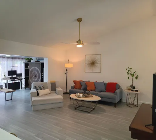 Vaulted ceilings, a gold-finish ceiling fan, recessed lighting, and wood-finish flooring