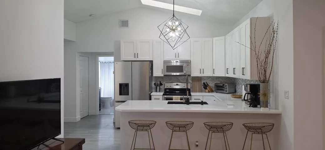 Kitchen featuring white cabinetry, stainless steel appliances, a breakfast bar, and a vaulted ceiling