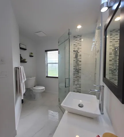Glass enclosed shower with tile accents and in wall niches for toiletries. Beautifully tiled flooring throughout bathrooms.