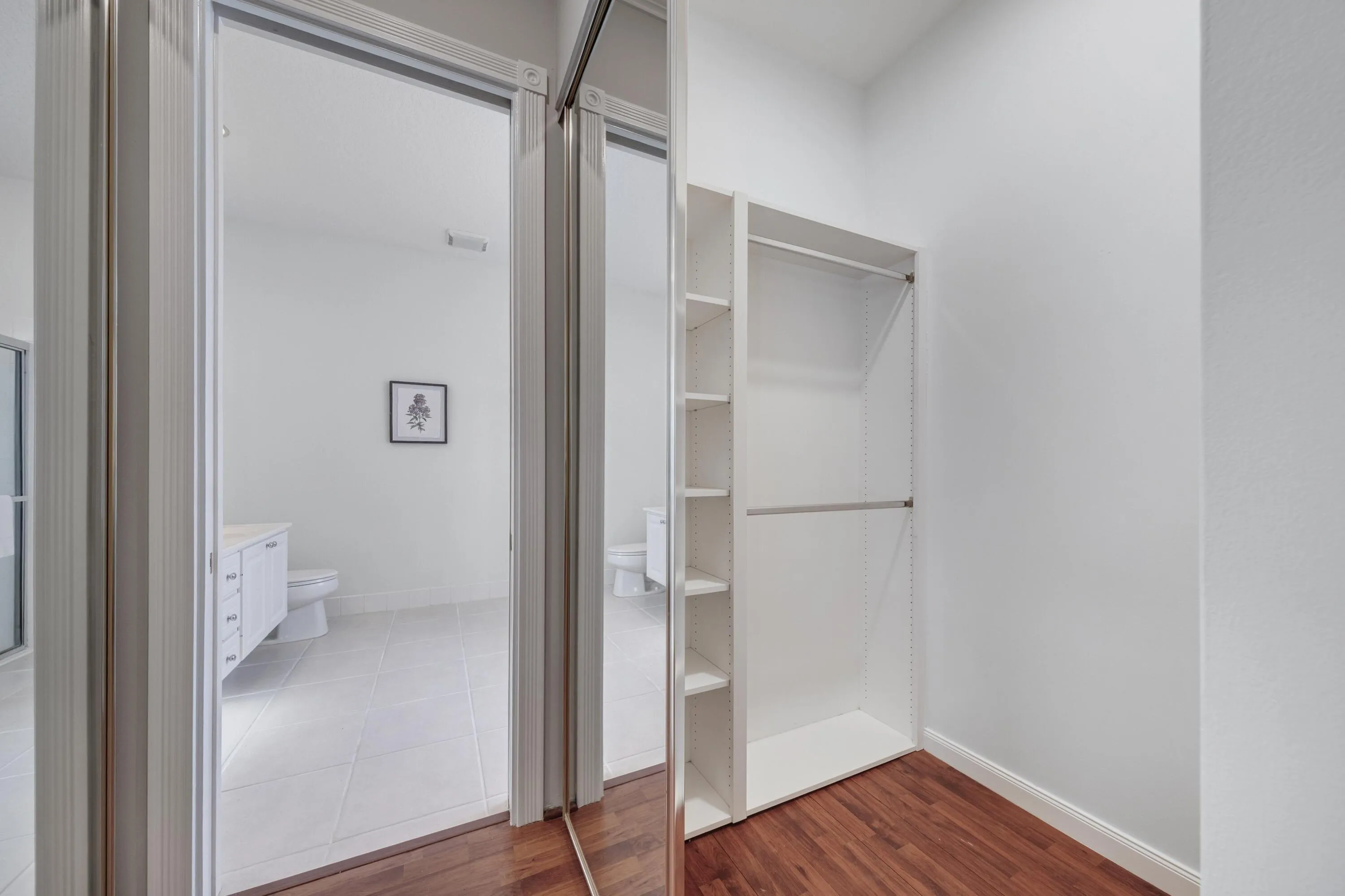 Primary closet with built-in shelving, opening to the primary bathroom