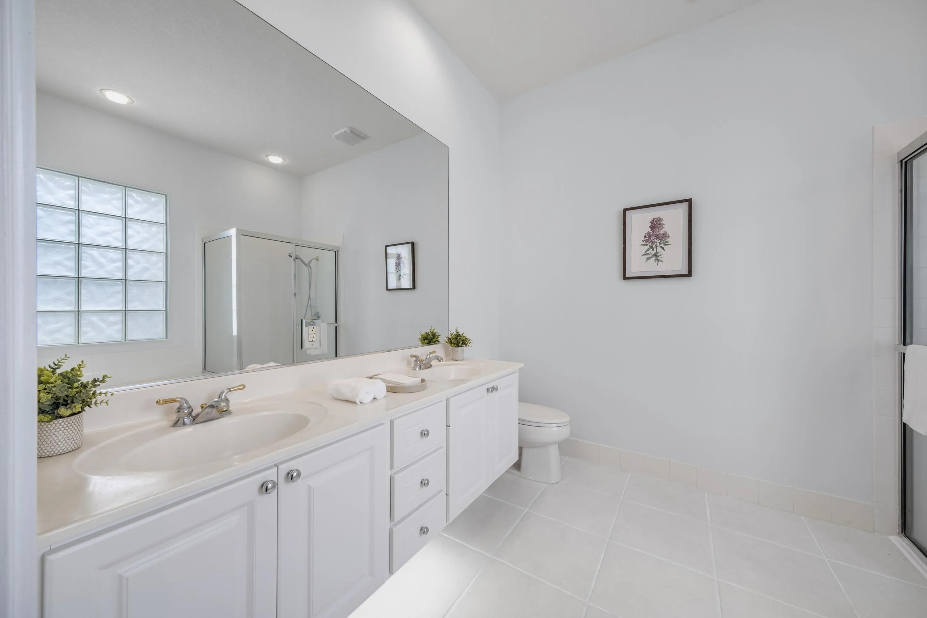 Primary bathroom with dual-sink vanity, glass block window and walk-in shower