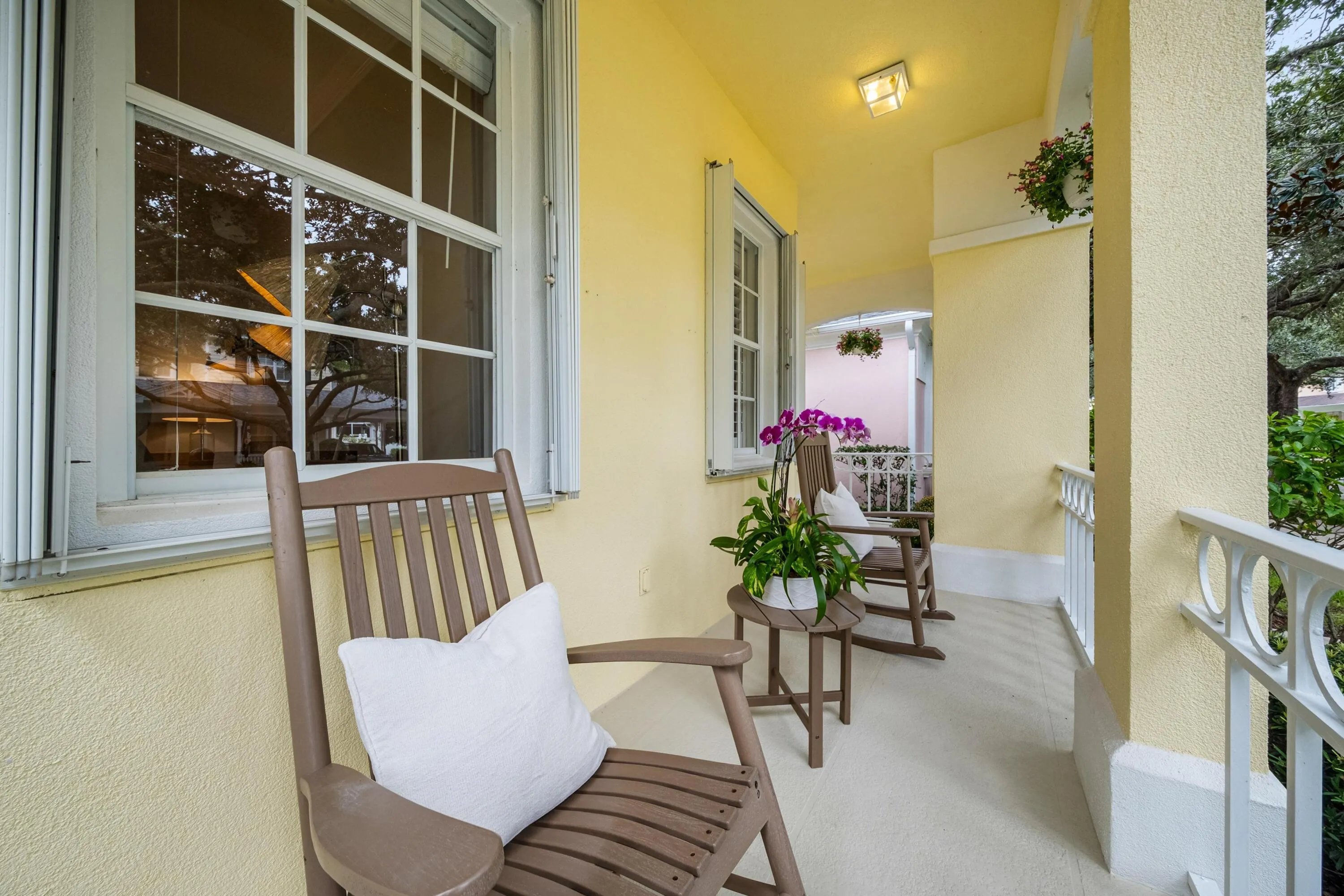 Covered front porch with room for seating, overlooking the oak-lined street