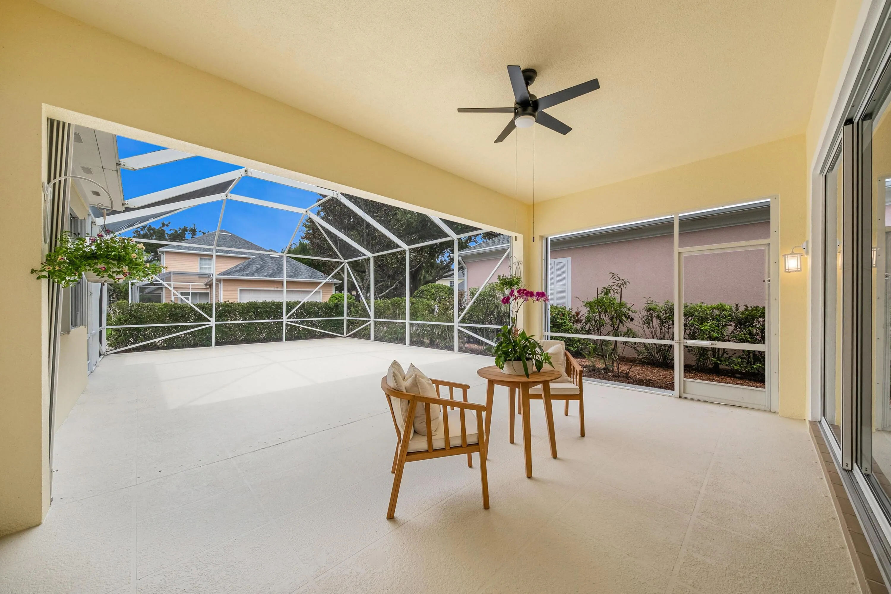 Covered seating area of the screened patio, with ceiling fan and open-air space behind