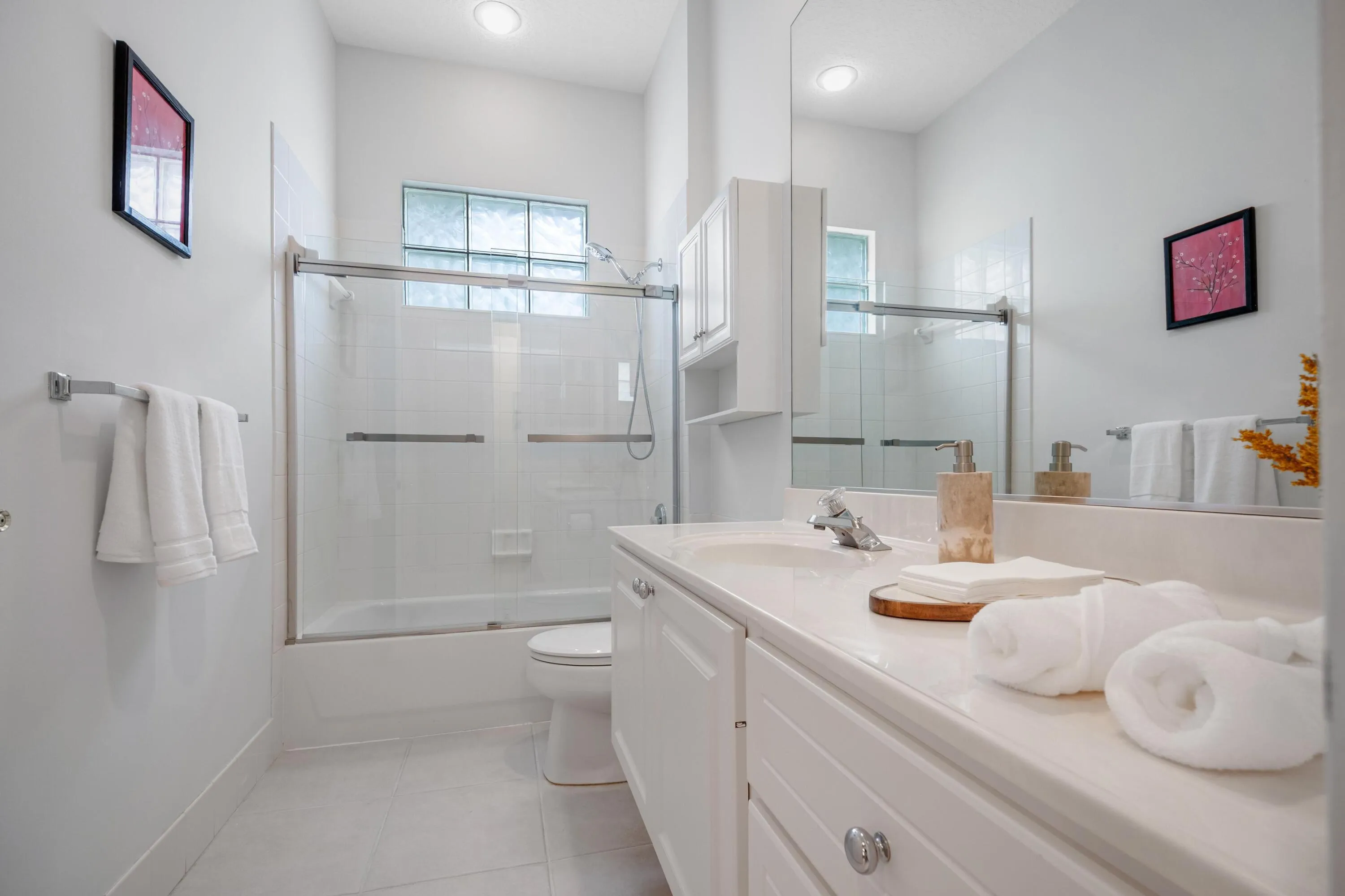Bathroom with a new glass shower enclosure over the tub and a glass block window