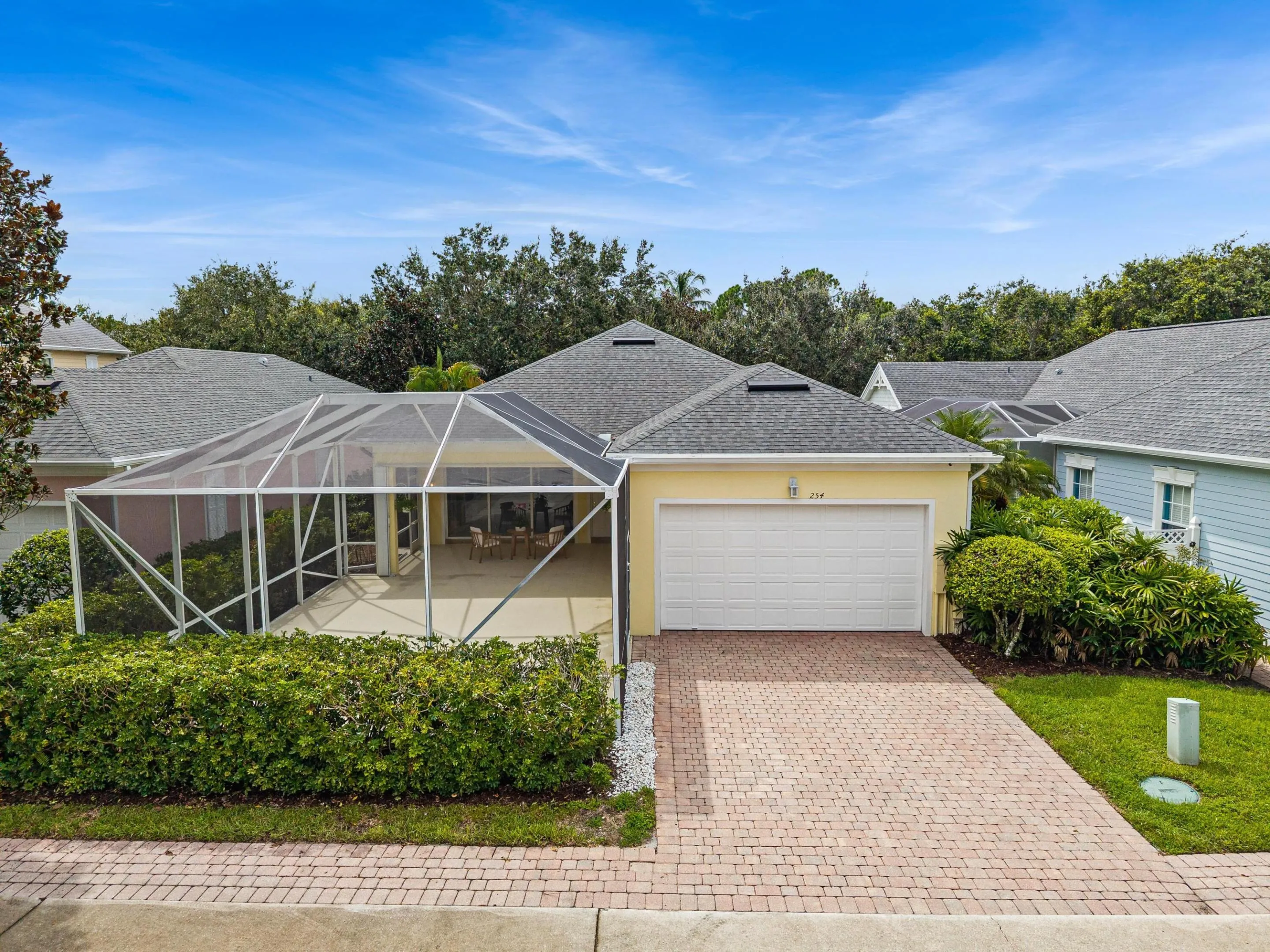 Rear elevation with two-car garage, paver driveway and screened patio enclosure