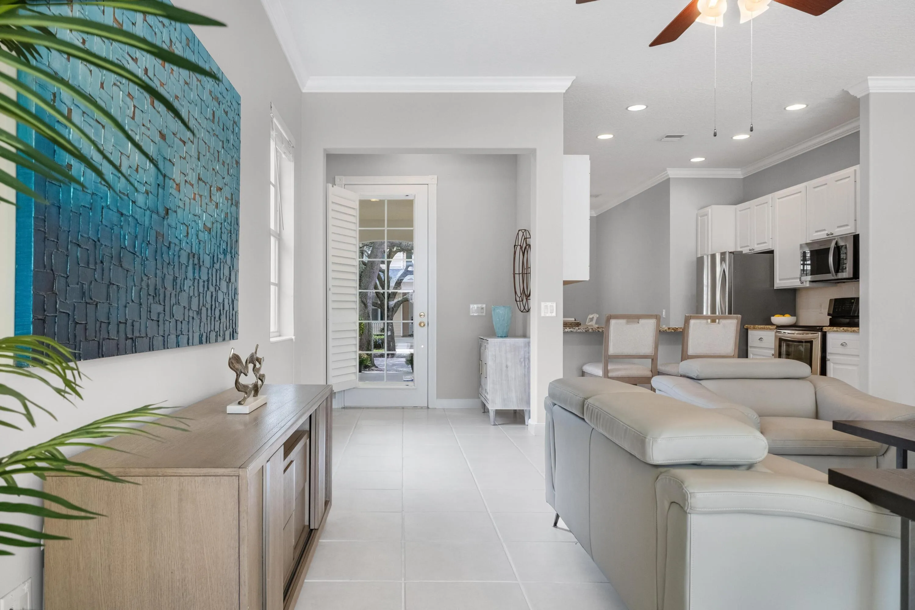 Foyer with plantation-shuttered entry door, opening to the living room and kitchen