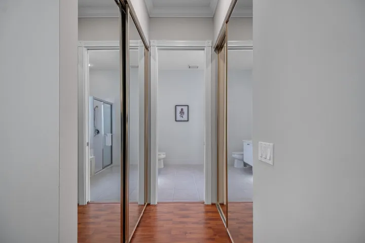 Passage to the primary bathroom, flanked by mirrored primary closets