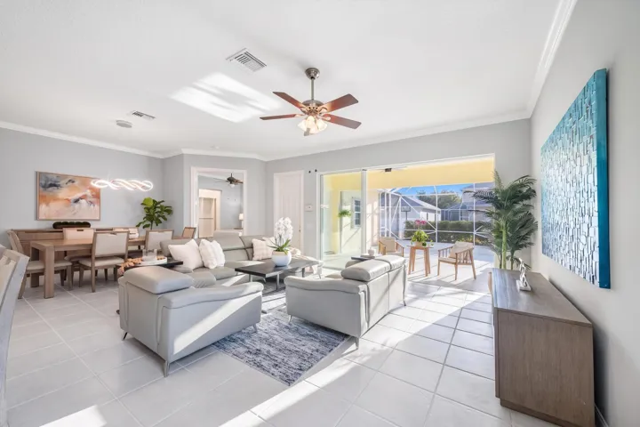 Living room with ceiling fan and sliders to the screened patio, and dining room