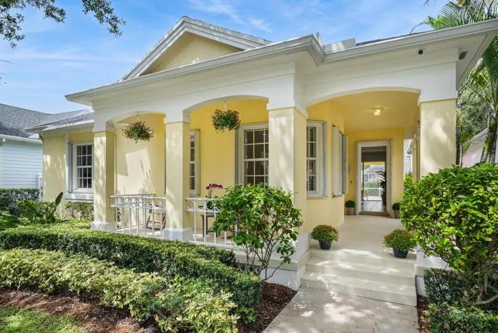 Covered front porch with arched colonnade, white railings and hanging flowers