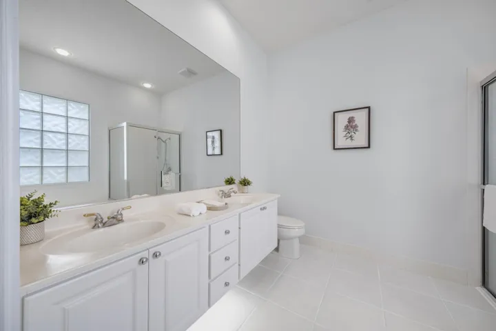 Primary bathroom with dual-sink vanity, glass block window and walk-in shower