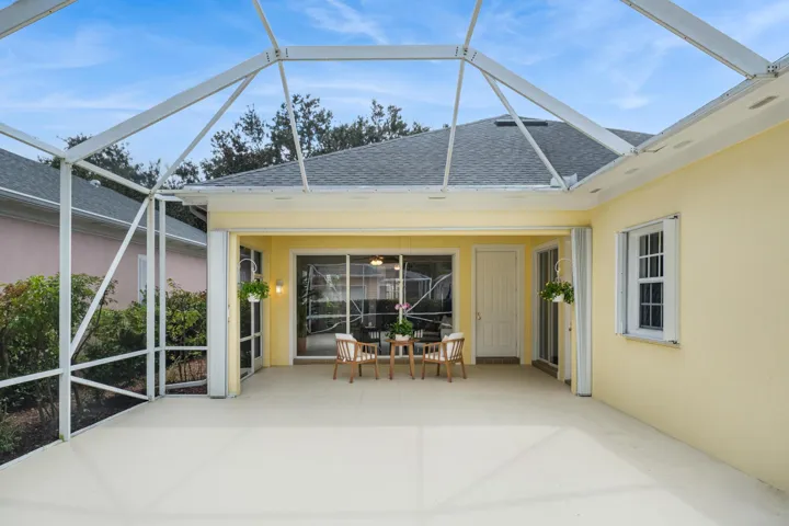 Screened patio view of the covered seating area, with multiple sliders into the home