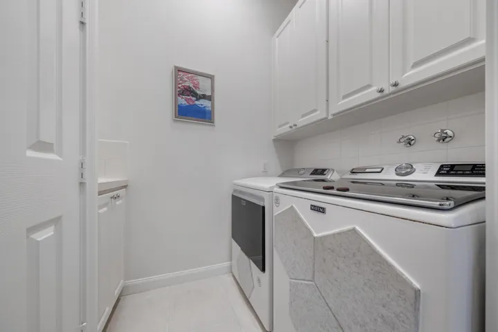 Laundry room with newer Maytag washer, dryer, upper cabinetry and utility sink to the left