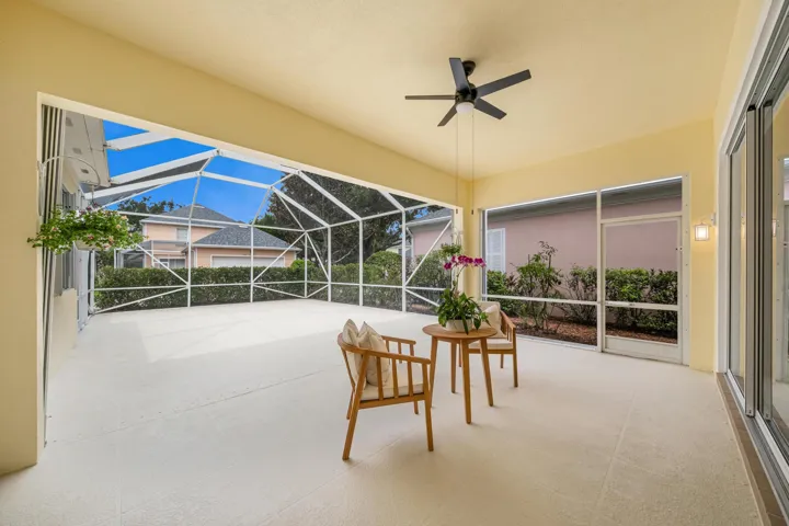 Covered seating area of the screened patio, with ceiling fan and open-air space behind