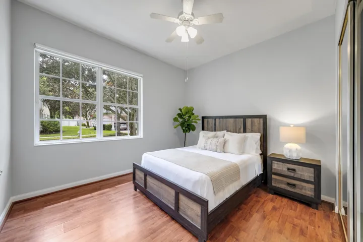 Bedroom with hardwood floors and a picture window framing the oak-lined street