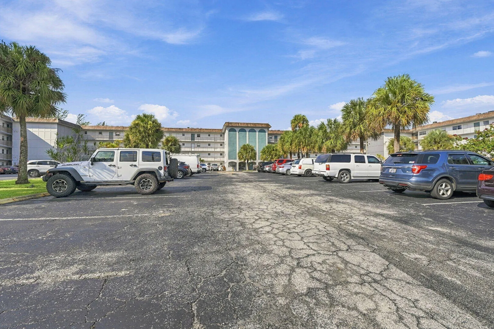 Multi-story building exterior with multiple windows, framed by mature palm trees