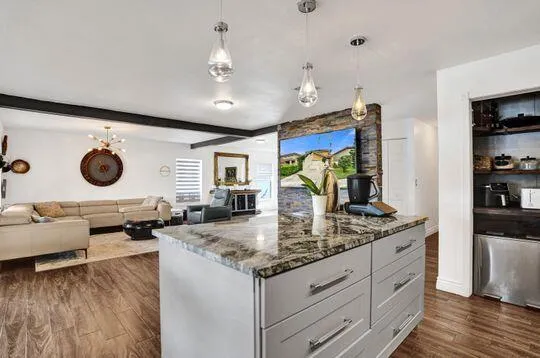 Kitchen island with a stone countertop and light gray cabinetry