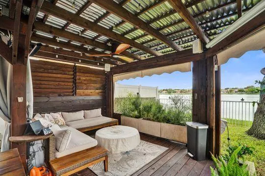 Covered outdoor living space featuring a corrugated metal roof, wood-beam ceiling, and a ceiling fan