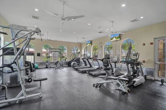 Fitness center featuring multiple exercise machines, arched windows, ceiling fans, recessed lighting, and rubber flooring