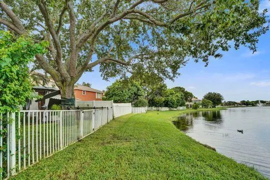 Expansive backyard featuring a manicured lawn, mature trees, and direct waterfront access
