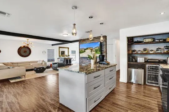 Kitchen island featuring a stone countertop, pendant lighting, and storage drawers