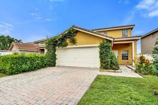 Two-story exterior with stucco finish, a two-car garage, and a paver driveway