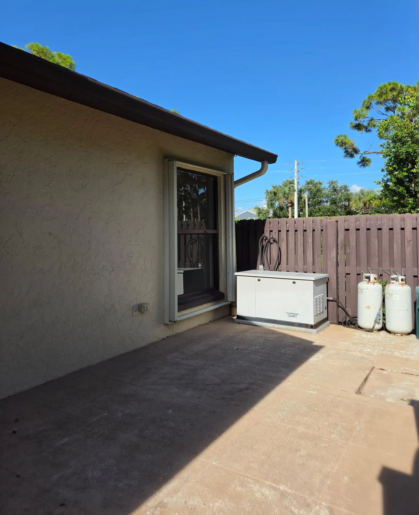 Concrete patio with stucco exterior and white window trim