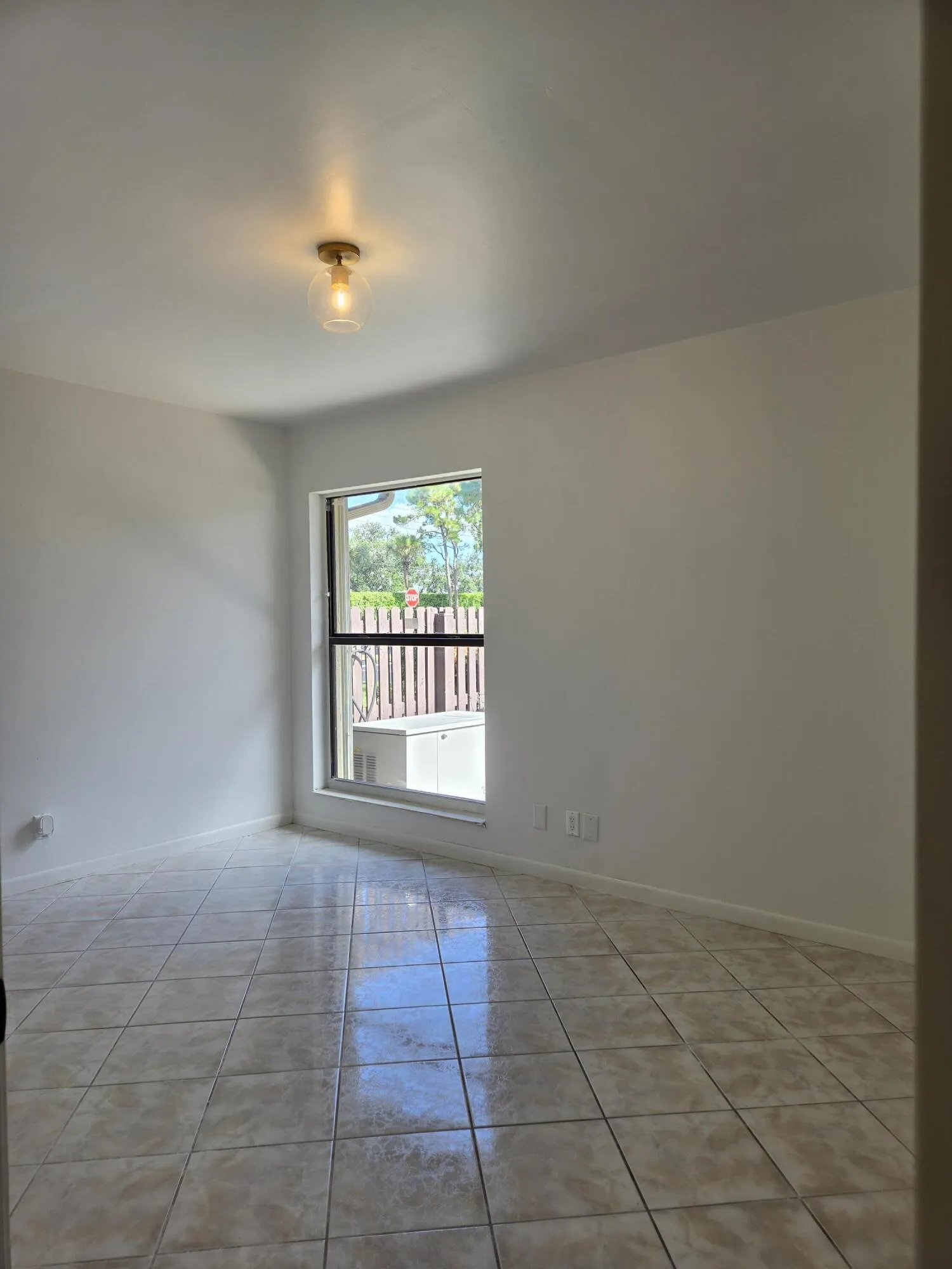 Tile flooring, window with exterior fencing, flush mount ceiling light fixture