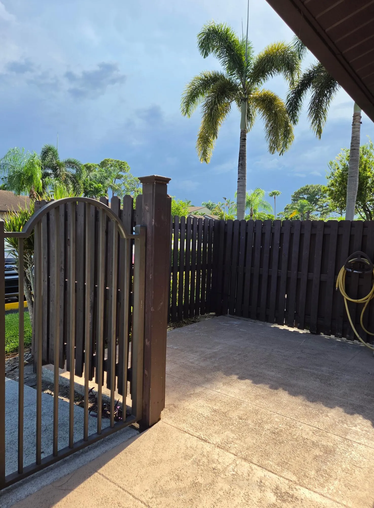 Gated entry to a private patio featuring a textured concrete surface and perimeter fencing