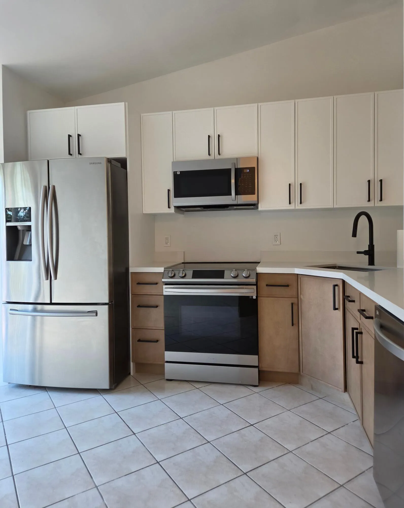 Stainless steel appliance suite, white upper cabinetry, wood-finish lower cabinetry, light-toned countertops, and tiled​​‌​​​​‌​​‌‌​‌‌​​​‌‌​‌​‌​‌​​​‌​​ flooring
