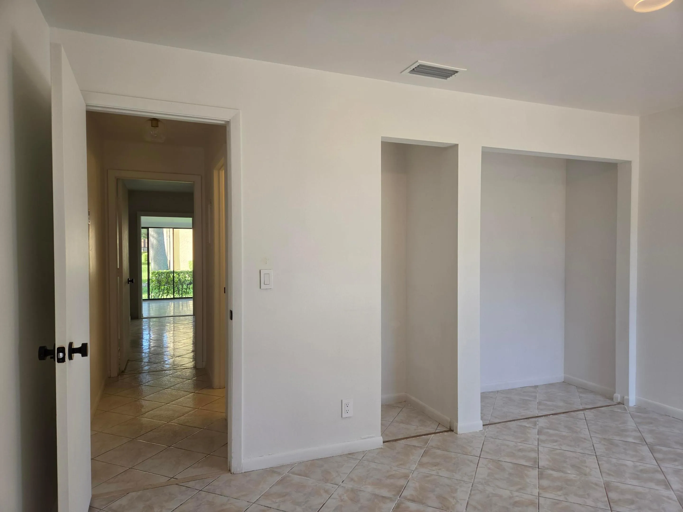 Neutral wall paint, light-toned square tile flooring, and integrated wall niches