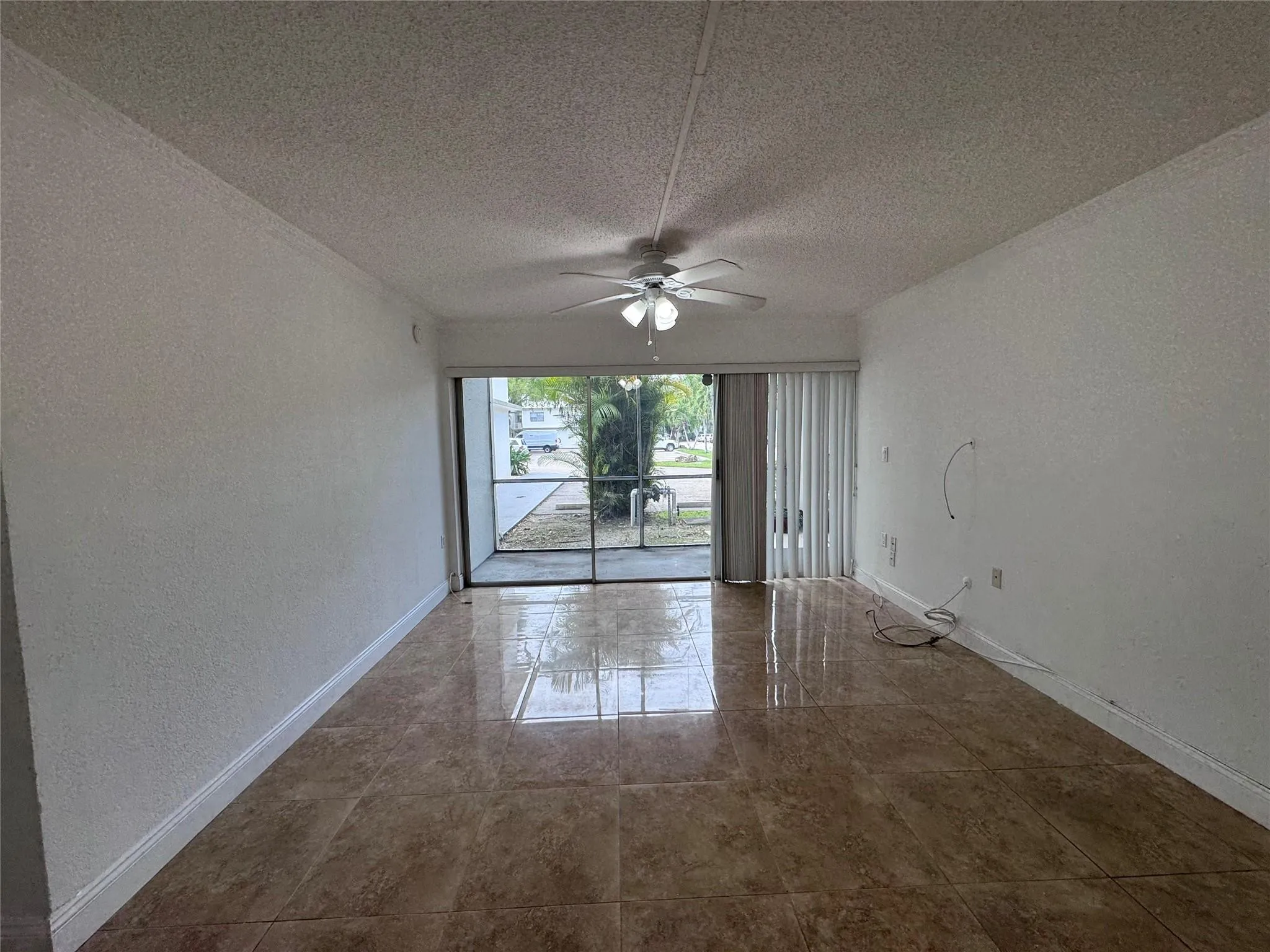 Polished tile flooring with a light-colored ceiling, ceiling fan, and sliding glass door leading to an outdoor screened area