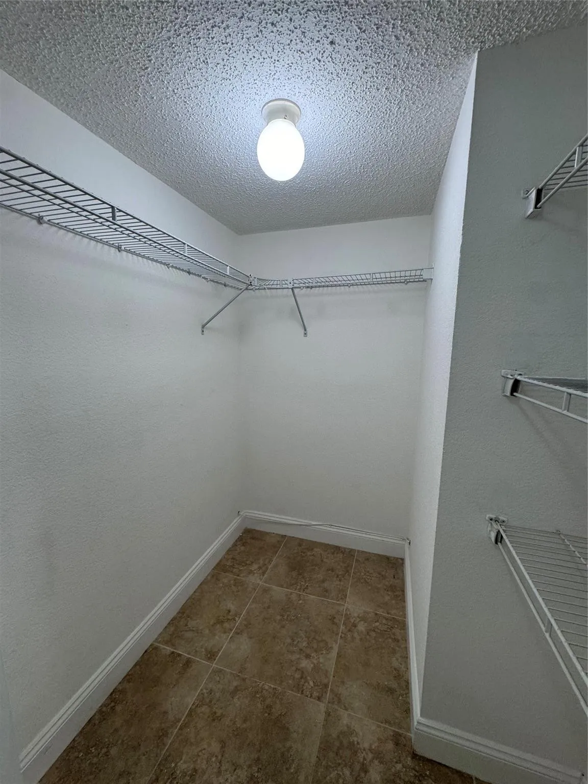 Recessed closet with tile flooring and wire shelving