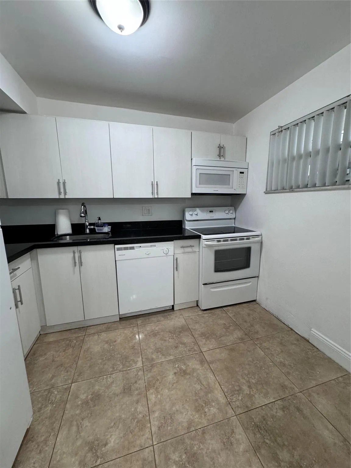 Kitchen featuring white cabinetry, dark countertops, a built-in microwave, an electric range, and tile flooring