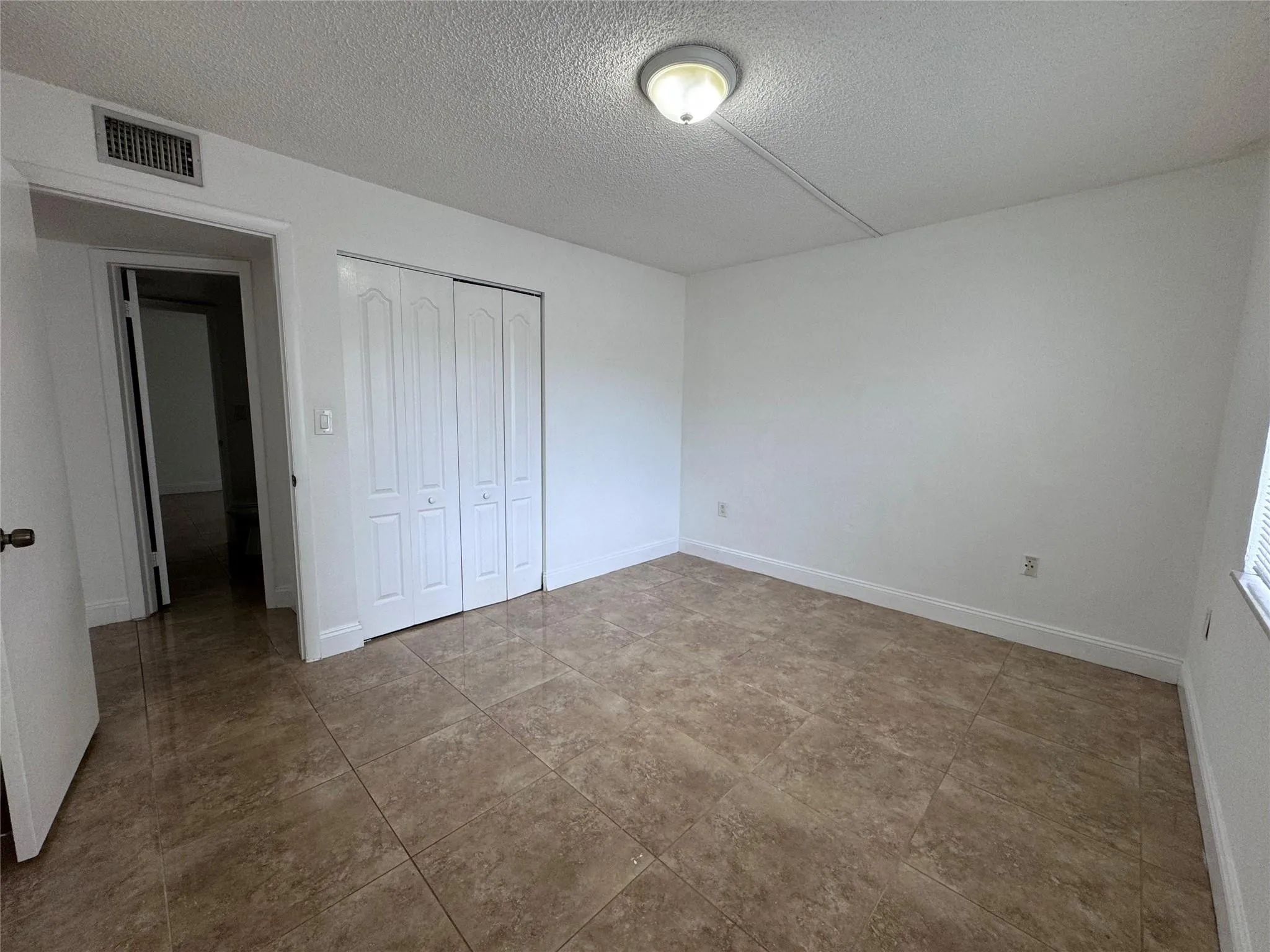 Neutral wall paint, tile flooring, bi-fold closet doors, and flush mount ceiling lighting