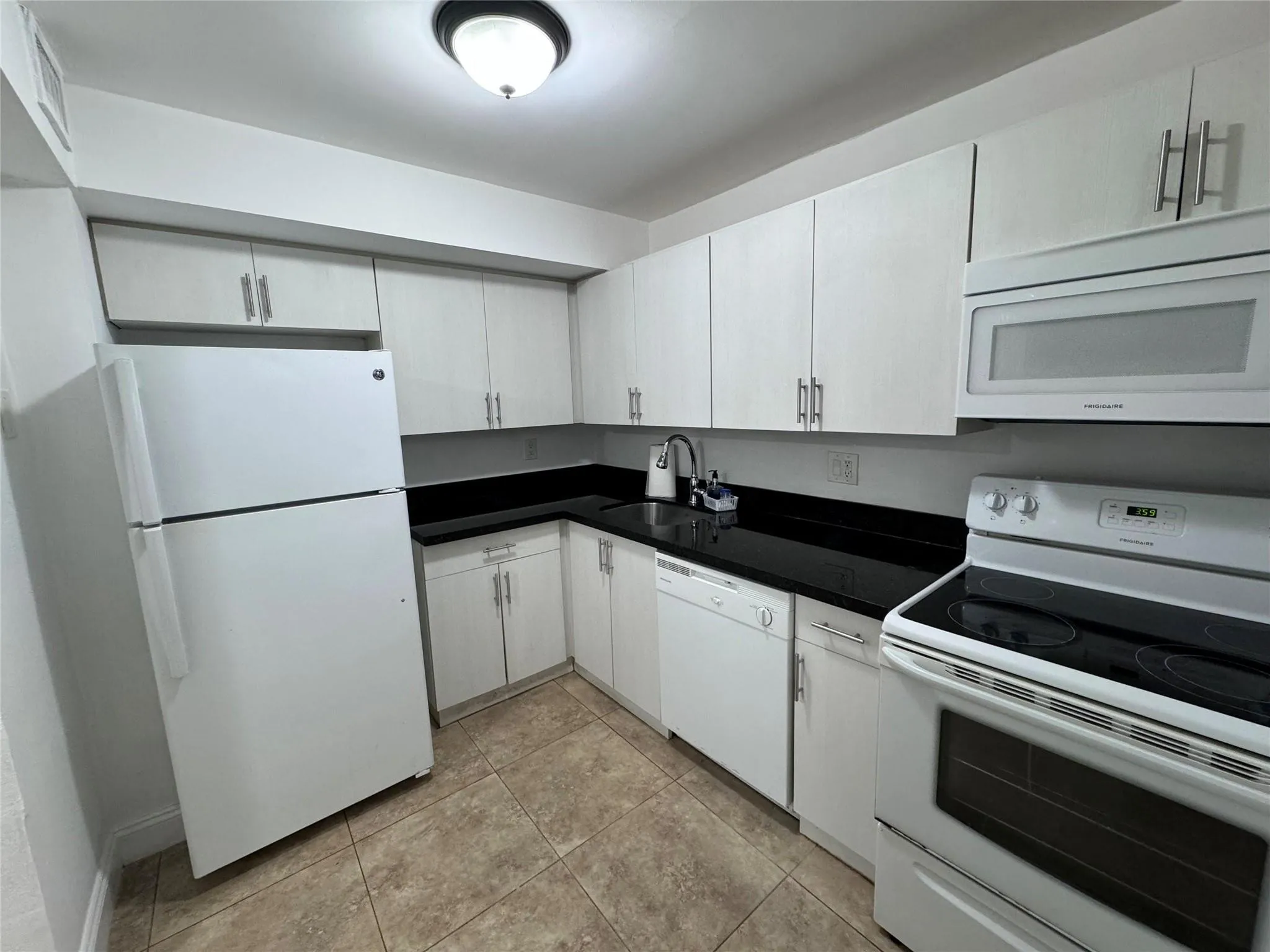 Kitchen featuring white cabinetry, black countertops, white appliances, and tiled flooring