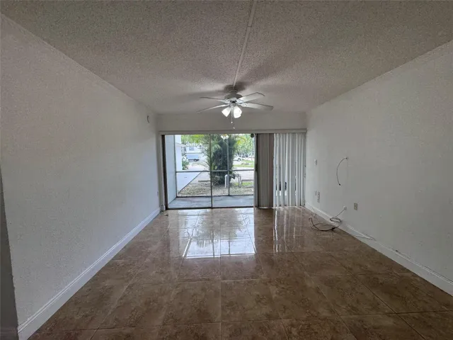 Polished tile flooring with a light-colored ceiling, ceiling fan, and sliding glass door leading to an outdoor screened area