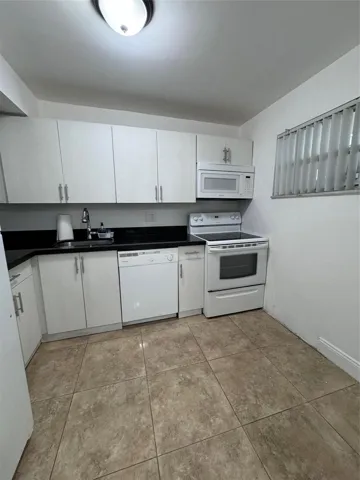 Kitchen featuring white cabinetry, dark countertops, a built-in microwave, an electric range, and tile flooring