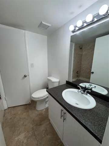 White vanity with dark speckled countertop, undermount sink, and chrome fixtures