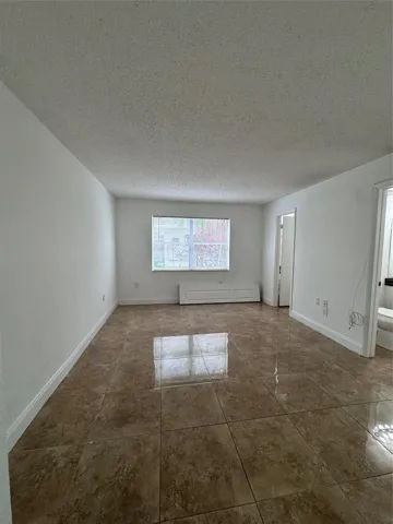 Glossy large-format tile flooring, window with blinds, and white painted walls
